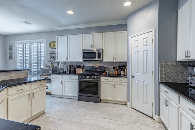 kitchen with appliances with stainless steel finishes, backsplash, a textured ceiling, and white cabinetry