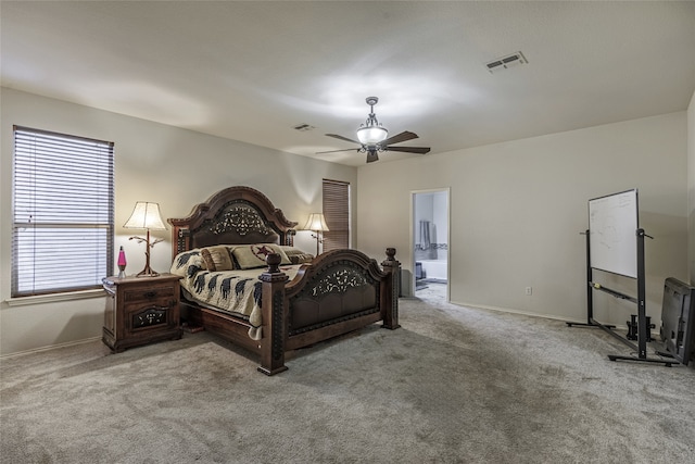 bedroom with ceiling fan, light colored carpet, and ensuite bathroom