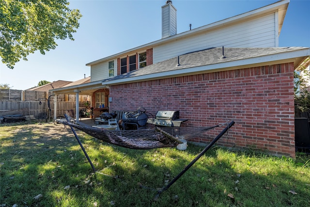 rear view of house featuring a lawn and a patio area