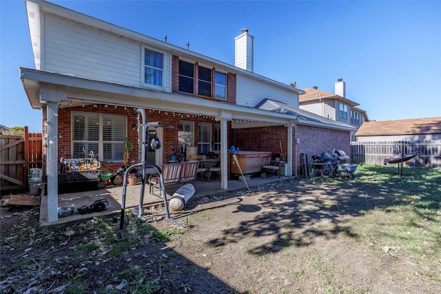 rear view of property with a hot tub and a patio area