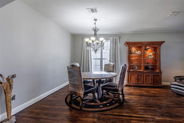 dining area featuring a textured ceiling, dark wood-type flooring, and a chandelier