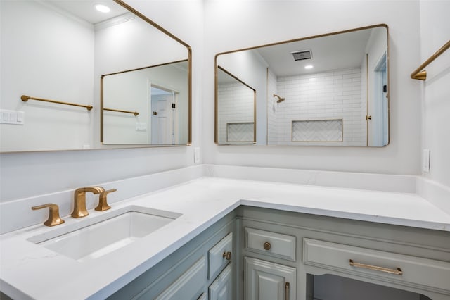 bathroom featuring vanity, ornamental molding, and tiled shower