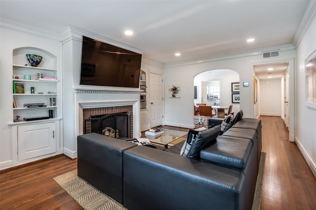 living room featuring crown molding, a fireplace, built in features, and dark hardwood / wood-style flooring