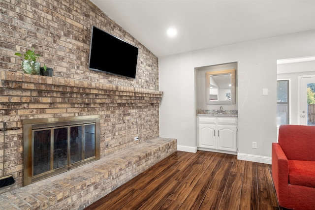 living room with lofted ceiling, sink, a brick fireplace, and dark hardwood / wood-style flooring