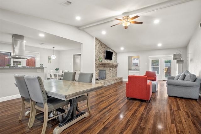 dining area featuring vaulted ceiling with beams, a brick fireplace, ceiling fan, and dark hardwood / wood-style flooring