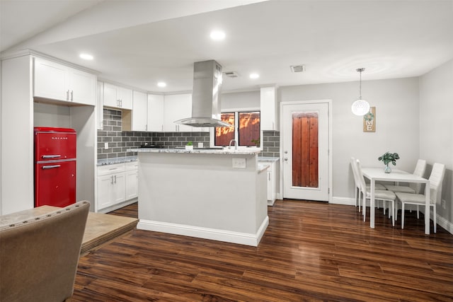 kitchen with island range hood, dark hardwood / wood-style floors, white cabinetry, light stone counters, and tasteful backsplash