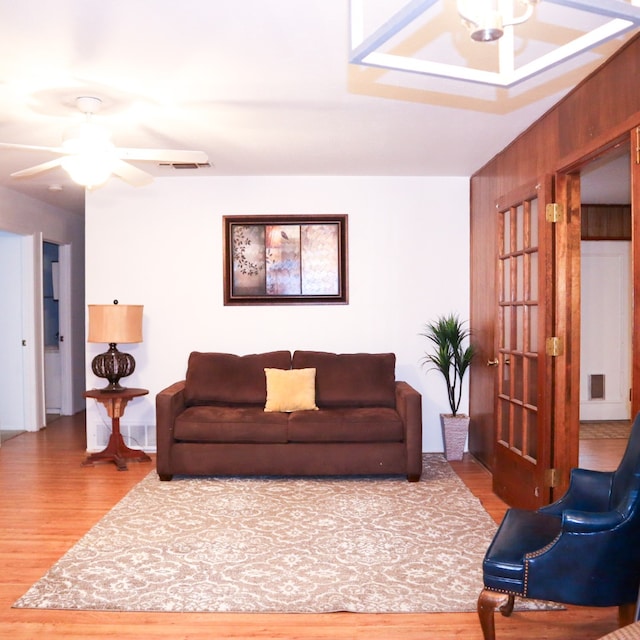 living room with ceiling fan, wooden walls, and hardwood / wood-style floors