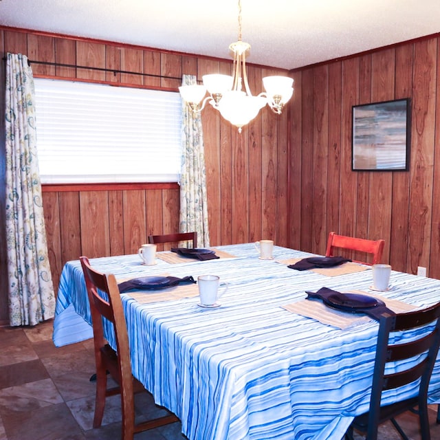 dining space with a notable chandelier, wood walls, and a textured ceiling