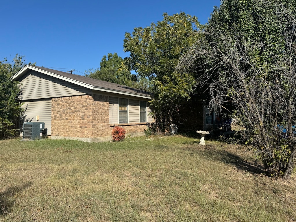 view of property exterior with central AC and a lawn