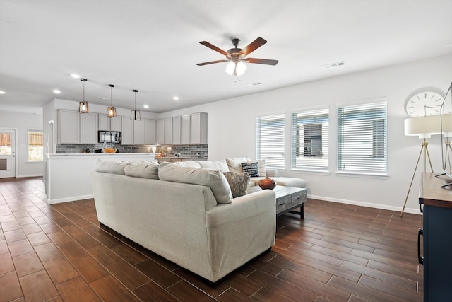 living room with dark hardwood / wood-style floors, a healthy amount of sunlight, and ceiling fan