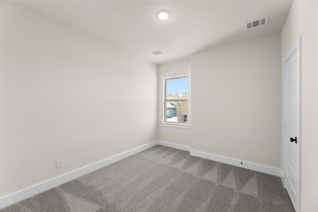 unfurnished bedroom with dark colored carpet, visible vents, and baseboards