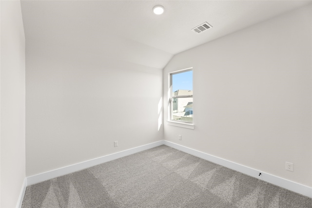 unfurnished room with lofted ceiling, carpet, visible vents, and baseboards