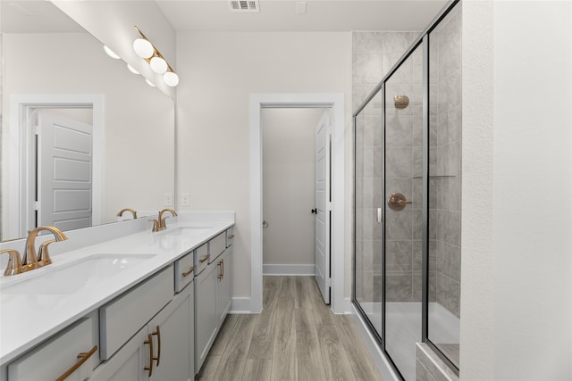 full bath featuring wood finished floors, a sink, visible vents, and a shower stall