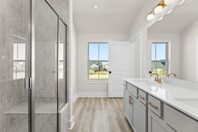 bathroom featuring a stall shower, plenty of natural light, a sink, and wood finished floors