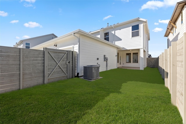 rear view of property featuring central air condition unit, a fenced backyard, a gate, and a yard