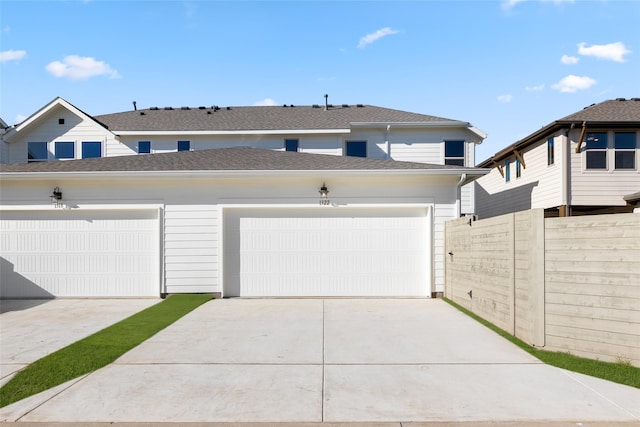 garage featuring concrete driveway and fence