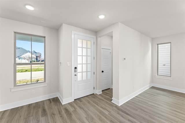 foyer entrance with light wood-style floors and baseboards