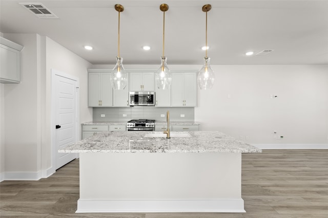 kitchen featuring tasteful backsplash, visible vents, stainless steel appliances, light wood-type flooring, and a sink