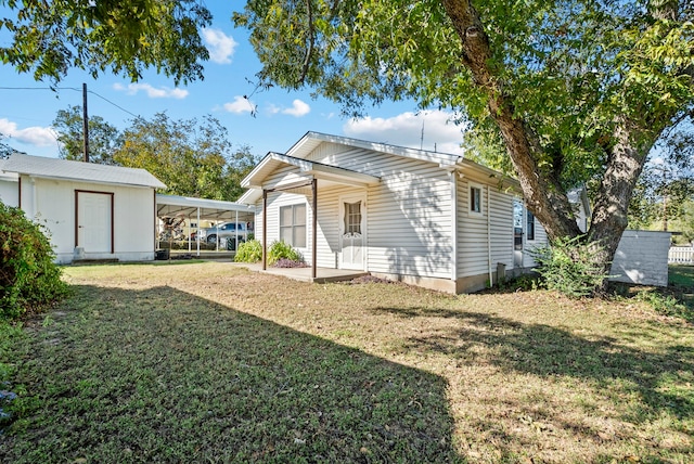 back of house featuring a carport and a lawn