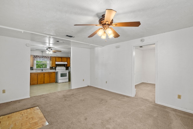 unfurnished living room with sink, light colored carpet, a textured ceiling, and ceiling fan