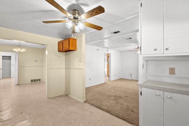 carpeted spare room with a textured ceiling and ceiling fan with notable chandelier