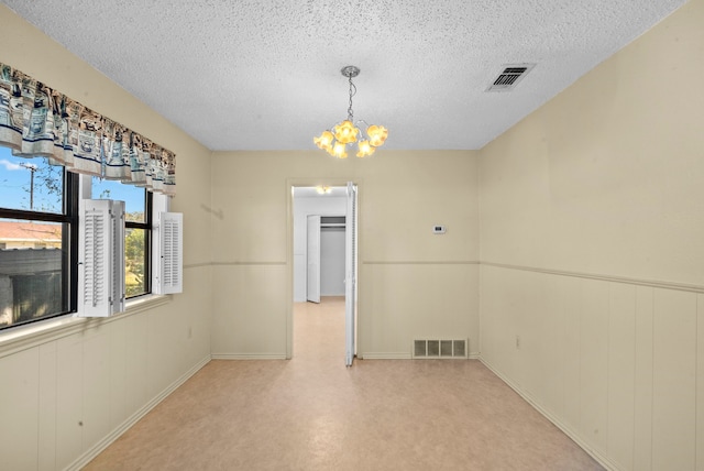 empty room with a textured ceiling and an inviting chandelier