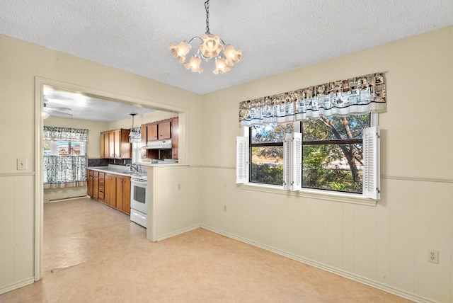 kitchen featuring sink, ceiling fan with notable chandelier, a textured ceiling, white range oven, and decorative light fixtures