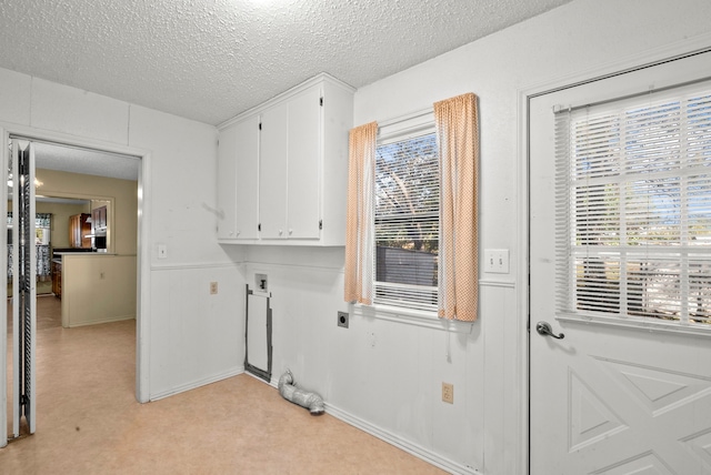 laundry area with hookup for an electric dryer, light carpet, a textured ceiling, and cabinets