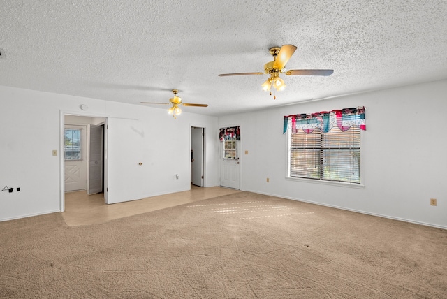 spare room with ceiling fan, a healthy amount of sunlight, a textured ceiling, and light colored carpet