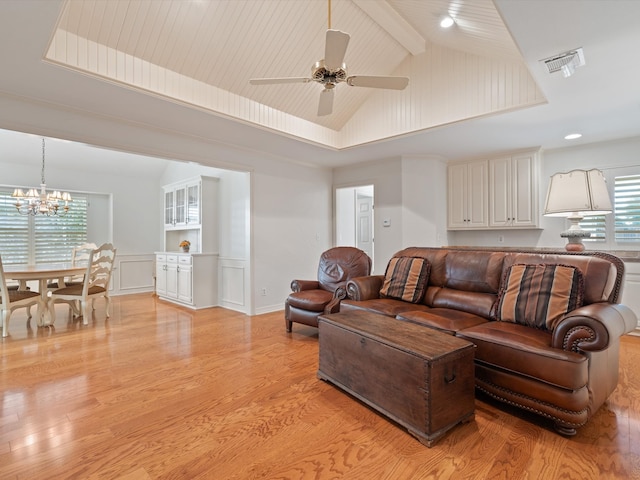 living room featuring lofted ceiling with beams, ceiling fan with notable chandelier, light wood-type flooring, and a wealth of natural light