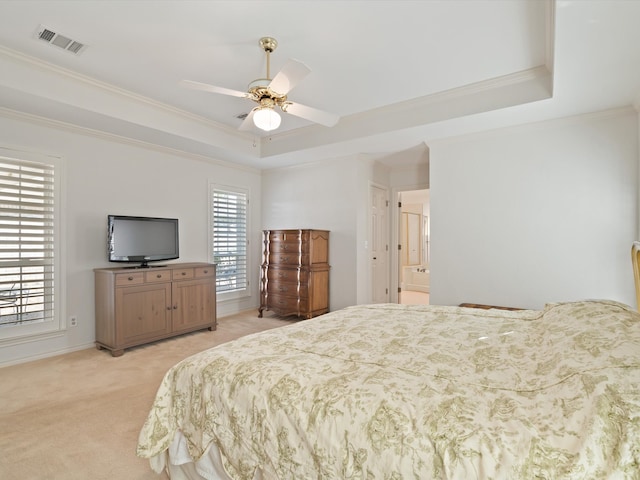 carpeted bedroom with ceiling fan, a raised ceiling, ornamental molding, and ensuite bathroom