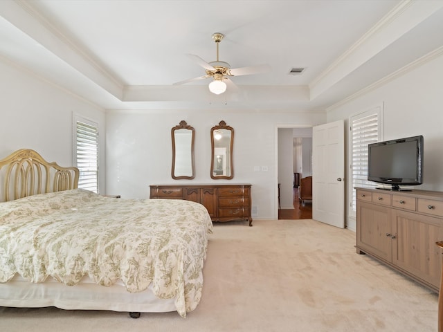 carpeted bedroom featuring crown molding, a raised ceiling, and ceiling fan