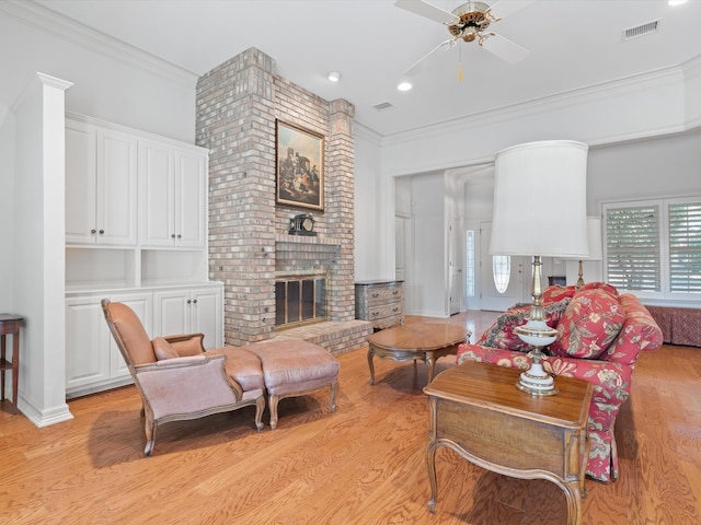 living room with crown molding, a fireplace, light hardwood / wood-style floors, and ceiling fan