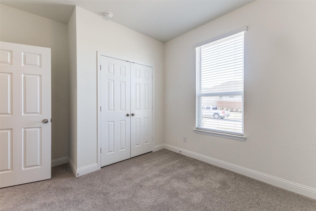 unfurnished bedroom featuring multiple windows, light carpet, and a closet