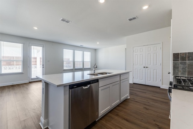 kitchen with sink, dark wood-type flooring, appliances with stainless steel finishes, a kitchen island with sink, and white cabinets