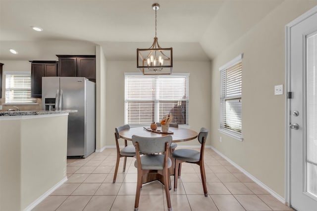 dining space featuring lofted ceiling, light tile patterned floors, and an inviting chandelier