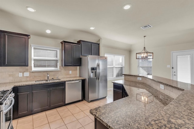 kitchen with light tile patterned floors, stainless steel appliances, decorative light fixtures, dark brown cabinetry, and sink