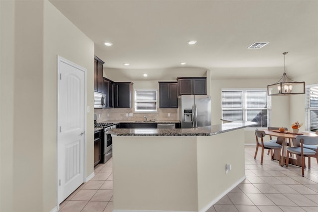 kitchen with light tile patterned flooring, stainless steel appliances, sink, and a center island