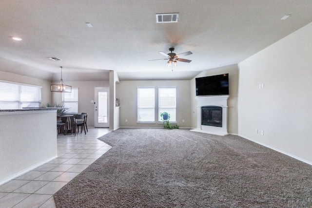 unfurnished living room featuring ceiling fan with notable chandelier, a textured ceiling, and light tile patterned flooring