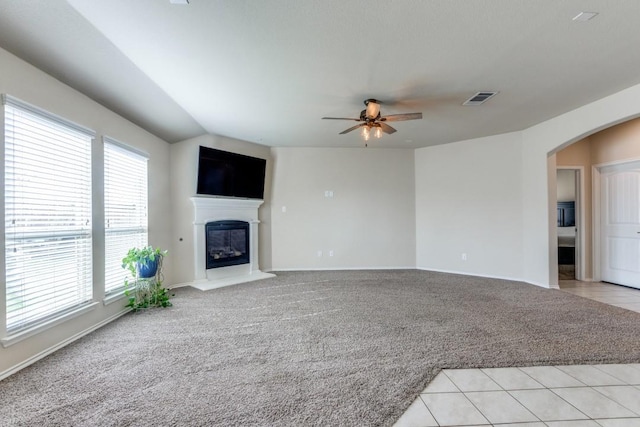 unfurnished living room featuring vaulted ceiling, ceiling fan, a wealth of natural light, and light colored carpet