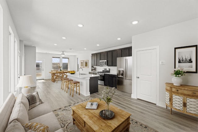 living room featuring recessed lighting, a ceiling fan, and light wood-style floors