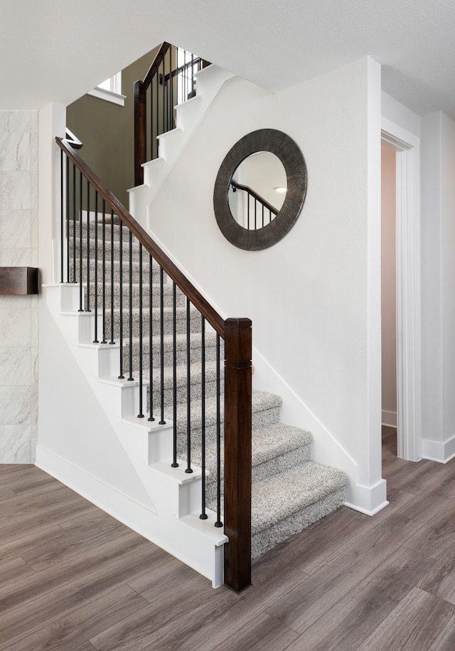 staircase featuring baseboards and wood finished floors