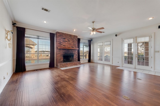 unfurnished living room with a brick fireplace, ceiling fan, crown molding, and french doors