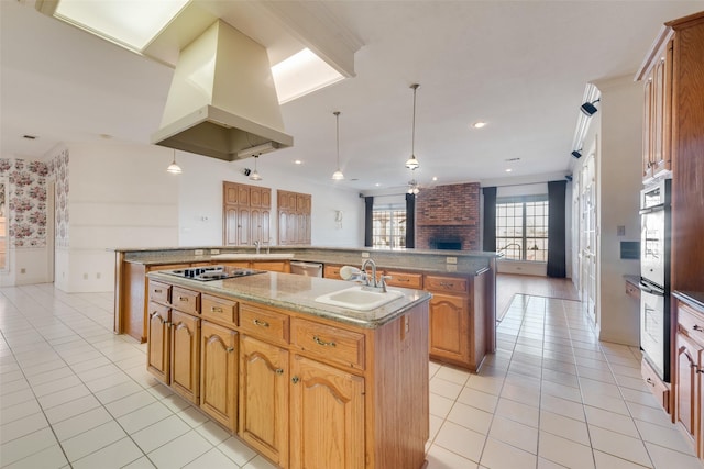 kitchen featuring sink, stainless steel dishwasher, pendant lighting, island range hood, and a center island with sink