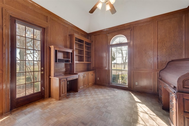 unfurnished office featuring ceiling fan, wood walls, and light parquet floors