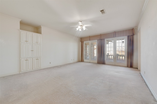 carpeted empty room featuring ceiling fan, crown molding, and french doors