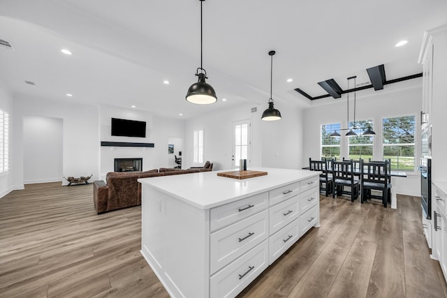 kitchen with white cabinets, pendant lighting, a center island, and light hardwood / wood-style floors