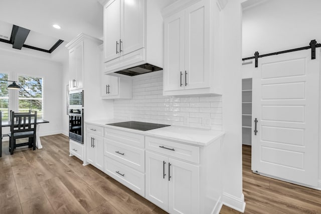 kitchen featuring white cabinetry, tasteful backsplash, beamed ceiling, black electric stovetop, and light wood-type flooring