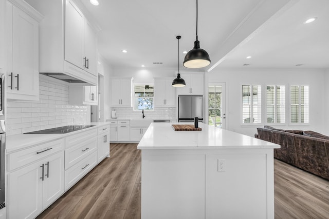 kitchen featuring white cabinets, black electric stovetop, and a center island