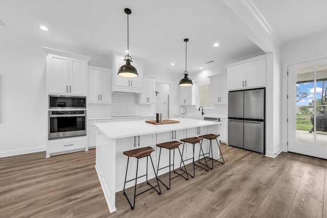 kitchen with decorative backsplash, appliances with stainless steel finishes, light hardwood / wood-style floors, and white cabinetry